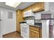 Kitchen featuring wood cabinets, white appliances and black countertops at 8225 Fairmount Dr # 102, Denver, CO 80247