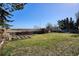 Scenic backyard view with mature trees, pergola, planting beds, wooden fence and expansive views of fields at 14259 W Virginia Dr, Lakewood, CO 80228