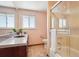 Bright bathroom featuring shower over tub, neutral tiles, large vanity counter and sink, window and fixtures at 14259 W Virginia Dr, Lakewood, CO 80228
