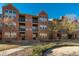 Multi-story brick condo building with private balconies and manicured lawn under a clear blue sky at 9633 E 5Th Ave # 10208, Denver, CO 80230
