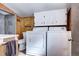 View of the bathroom with a toilet, washer, and dryer; features wood paneling and cabinetry at 2401 W Jewell Ave, Denver, CO 80219