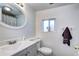 Cozy bathroom with white walls and gray vanity plus updated mirror and lighting at 2401 W Jewell Ave, Denver, CO 80219
