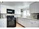 Bright kitchen features white cabinets, granite counters, subway tile backsplash and black gas range at 2401 W Jewell Ave, Denver, CO 80219