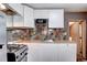 Close-up view of the kitchen featuring white cabinetry, colorful backsplash, and stainless appliances at 2401 W Jewell Ave, Denver, CO 80219