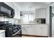 Bright kitchen features white cabinets, granite counters, subway tile backsplash and black gas range at 2401 W Jewell Ave, Denver, CO 80219