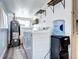Functional laundry room with washer, dryer, shelving, hot water tank, and laminate flooring at 2401 W Jewell Ave, Denver, CO 80219