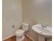 This bathroom features a white toilet and pedestal sink against neutral walls, accented by brown tiled flooring at 331 Las Lomas St, Brighton, CO 80601