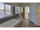 Elegant bathroom features a large bathtub, a glass shower, and natural light from the window at 331 Las Lomas St, Brighton, CO 80601