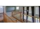 Open hallway with wood railing, neutral carpet, a ceiling fan, and natural light from the large windows at 331 Las Lomas St, Brighton, CO 80601