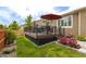 Wooden backyard patio with furniture, umbrella, green lawn, and flower bed at 3936 Costillo Ct, Brighton, CO 80601