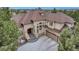Elegant stucco home featuring a three-car garage, complemented by lush pine trees, blue sky, and distant mountain views at 9132 Scenic Pine Dr, Parker, CO 80134