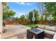 Spacious backyard features a stone patio, green lawn, firepit, seating, and mature trees at 14794 Vine St, Thornton, CO 80602