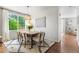 Bright dining room with seating for six, modern light fixture, and large window overlooking greenery at 14794 Vine St, Thornton, CO 80602