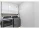 Laundry room with front load washer and dryer and overhead white cabinets at 14794 Vine St, Thornton, CO 80602