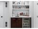 A stylish wet bar with a sink, dark wood cabinets, and a beverage refrigerator at 14794 Vine St, Thornton, CO 80602