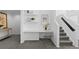 Hallway featuring built-in desk, shelving, neutral paint, and gray carpet leading up the stairs at 221 S Garfield St # 213, Denver, CO 80209