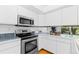 Bright kitchen with stainless steel appliances, white cabinetry, and tiled backsplash at 221 S Garfield St # 213, Denver, CO 80209