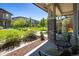 Inviting covered porch with brick pillars, outdoor seating, and views of the lush green space at 11033 E 28Th Pl, Denver, CO 80238