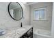Modern bathroom with marble-style walls, granite countertops, a round mirror, and a tub for relaxing at 3090 S High St, Denver, CO 80210