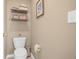 Compact powder room featuring toilet, floating shelf, and decor at 4808 S Picadilly Ct, Aurora, CO 80015