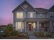 Charming two-story home featuring a cozy front porch, landscaped yard, and a beautiful dusk sky at 3921 E 141St Ave, Thornton, CO 80602