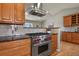 Gourmet kitchen with Wolf range, custom hood, wood cabinets, and granite counters perfect for culinary enthusiasts at 3785 E 134Th Ct, Thornton, CO 80241