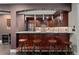Wet bar featuring wood cabinetry, granite counters, pendant lighting, with four stools, a stainless refrigerator and wine cooler at 5662 W Peakview Pl, Littleton, CO 80123