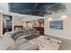 Spacious living room with a comfortable gray sectional sofa, stone fireplace, wet bar, and unique cloud ceiling design at 5662 W Peakview Pl, Littleton, CO 80123