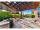 Outdoor patio with a built-in stone grill area, wooden pergola, and a beautiful view of the landscaped backyard at 5662 W Peakview Pl, Littleton, CO 80123