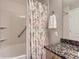Clean bathroom with a shower and tub, granite countertops, and a modern seashell-themed curtain at 8611 Gold Peak Dr # D, Highlands Ranch, CO 80130