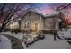 Tan two-story home with stone accents, snowy landscaping, and walkway at 1430 Whitehall Dr # 9A, Longmont, CO 80504