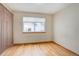 Bedroom with hardwood floors, large window, base molding, neutral paint, and decorative curtains on the side at 18292 E Caspian Pl, Aurora, CO 80013