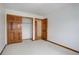 Bedroom with neutral carpet and walls, wood trim, and closet with wood doors at 18292 E Caspian Pl, Aurora, CO 80013