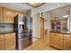Kitchen view with stainless refrigerator, wood floors and cabinetry, granite countertops, and an opening to a Gathering room at 18292 E Caspian Pl, Aurora, CO 80013