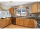 Kitchen with oak cabinets, stone backsplash, granite counters, stainless appliances, wood floors, and window overlooking backyard at 18292 E Caspian Pl, Aurora, CO 80013