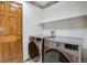 Laundry room with stainless washer and dryer, floral wallpaper border, white walls and door, and a white shelf at 18292 E Caspian Pl, Aurora, CO 80013