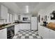 A kitchen with white cabinets, black countertops, and black and white checkered floors at 5011 Troy St, Denver, CO 80239