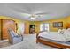 The bright main bedroom features a wooden armoire, neutral carpet, and ceiling fan at 5011 Troy St, Denver, CO 80239