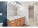Bathroom featuring dual sinks, wood cabinets, white countertops and a walk-in closet at 9757 Ash Ln, Thornton, CO 80229