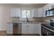 Updated kitchen features white cabinets, stainless steel appliances, stone countertops and modern fixtures at 6013 W 62Nd Ave, Arvada, CO 80033