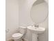 Compact powder room featuring a pedestal sink, oval mirror, and a standard toilet at 8895 San Antonio St, Littleton, CO 80125