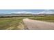 Paved road winding through a grassy landscape with mountains in the background at 8895 San Antonio St, Littleton, CO 80125