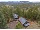 Panoramic aerial view of a home nestled within a dense forest with mountain views in the background at 27891 Columbine Rd, Evergreen, CO 80439