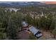 Picturesque aerial view of a home with lights at dusk, surrounded by trees and distant mountain views at 27891 Columbine Rd, Evergreen, CO 80439