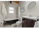 Bathroom features a vanity with dark wood cabinets, a soaking tub with shower, and white wainscoting at 27891 Columbine Rd, Evergreen, CO 80439
