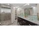 Modern bathroom with glass block shower, double sink vanity with marble countertop, and decorative mirrors at 27891 Columbine Rd, Evergreen, CO 80439