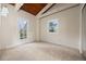 Bright bedroom features a wooden ceiling, soft carpet, a large window, and an exterior door leading to a balcony at 27891 Columbine Rd, Evergreen, CO 80439