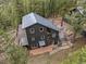 Aerial view of a modern black home with a metal roof, wooden deck, and lush surrounding trees at 27891 Columbine Rd, Evergreen, CO 80439