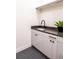 Modern laundry room with sleek cabinets, dark countertop, and stylish hexagon tile flooring at 3087 S Dexter Way, Denver, CO 80222