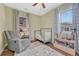 Bedroom with gray recliner, decorative curtains, books and a white crib with a side-rail at 3640 York St, Denver, CO 80205